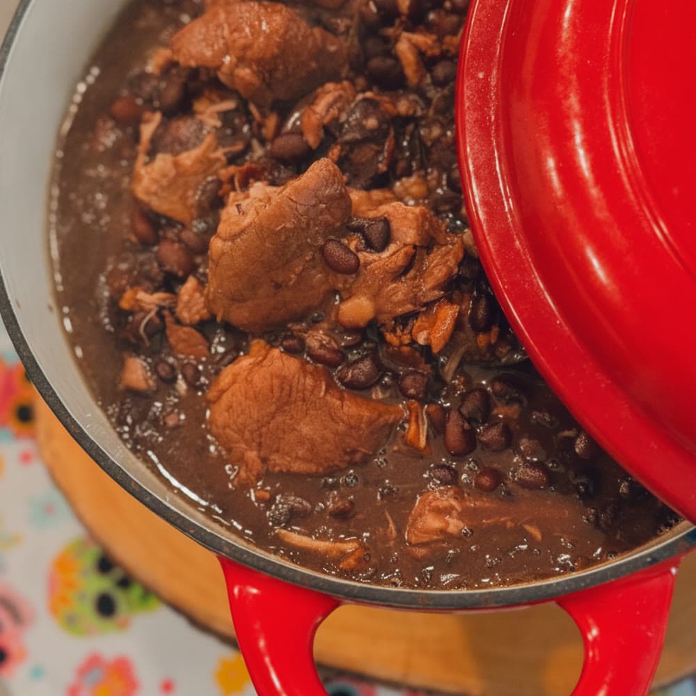 A steaming bowl of Brazilian feijoada, a black bean and pork stew, served with rice, farofa and orange slices at an Orlando event